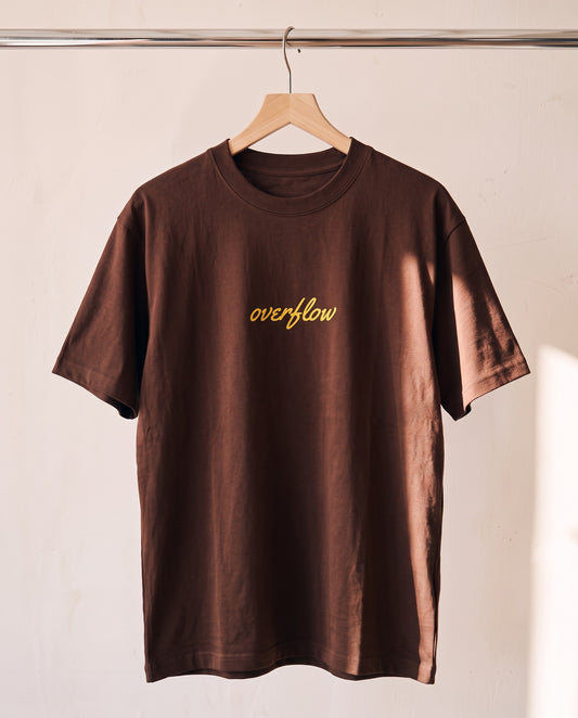 Overflow Christian tee in brown on a wood hanger, front