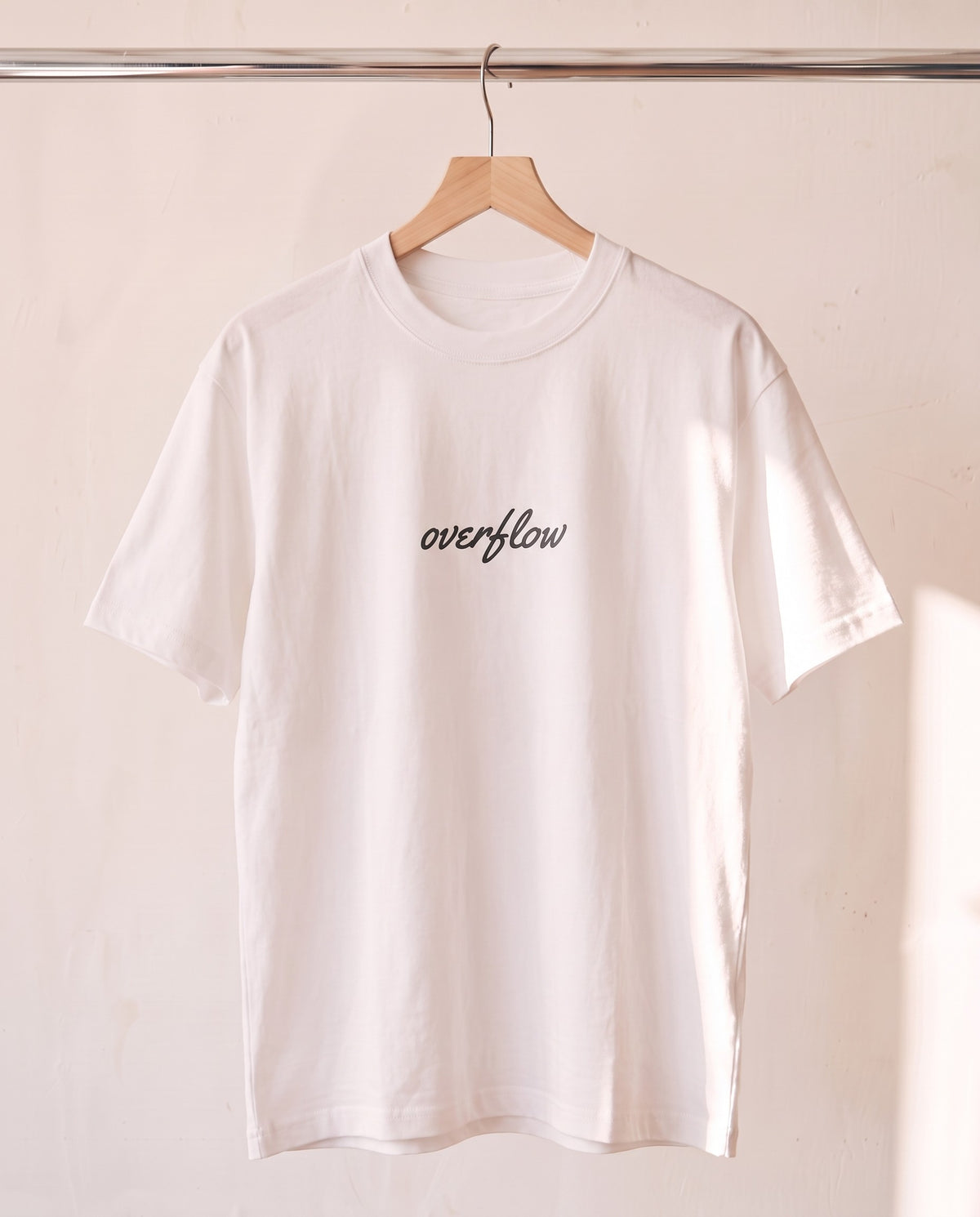 Overflow Christian tee in white on a wood hanger, front